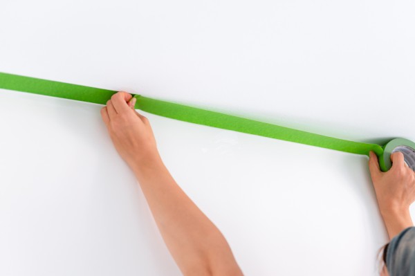 green frog tape being applied to the wall